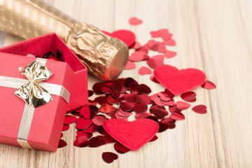 bottle of vine, red hearts and small present