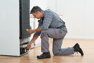 Technician Checking Fridge With Multimeter At Home