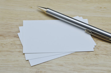 Blank business card with pencil on wooden table