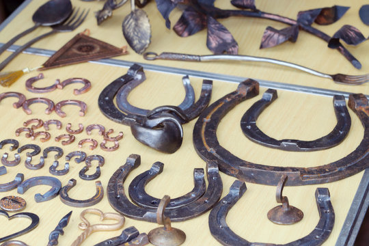 Many different metal horseshoes and forged objects are on table
