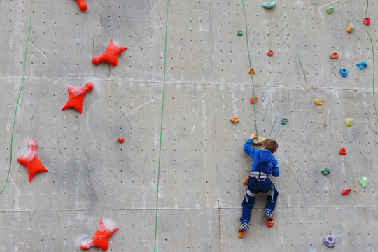 Back of boy climbing with rope on special wall for climbing