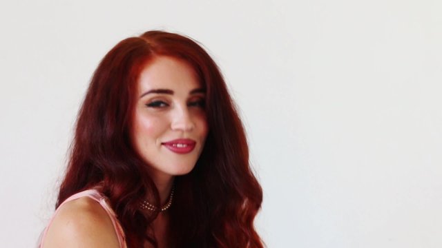 Pretty young woman with red hair looks at camera and confused

