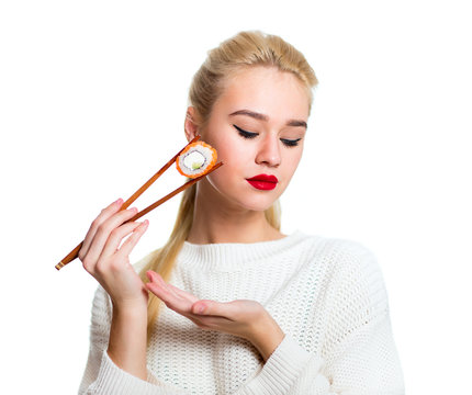 Young woman holding sushi with a chopsticks, isolated on white