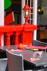 Menu and red candle on black tables of street cafe with red lant