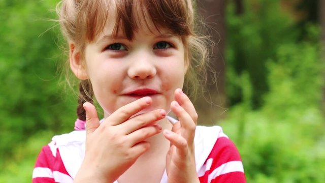 Little cute girl grimaces and laughs in summer park. Close up view

