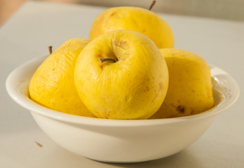 pile of yellow apples in a white bowl