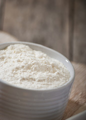 flour on white bowl in wooden background