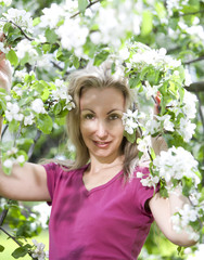 young attractive woman standing near the blossoming apple tree