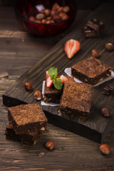 Homemade chocolate brownies with hazelnuts on grunge brown wooden background. Toned image. Selective focus