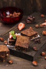 Homemade chocolate brownies with hazelnuts on grunge brown wooden background. Toned image. Selective focus