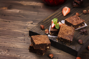 Homemade chocolate brownies with hazelnuts on grunge brown wooden background. Toned image. Selective focus