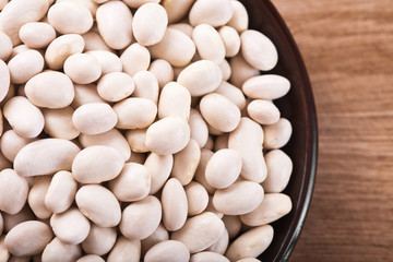 White beans in a brown plate on a wooden table