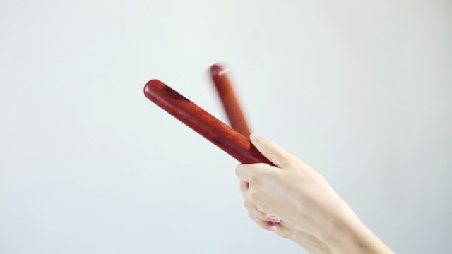 Hands playing on the musical sticks (percussion). Knock several times on a white background. Ethnic musical instruments.