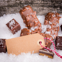 Auswahl an weihnachtsgebäck mit leerer Tafel im Schnee