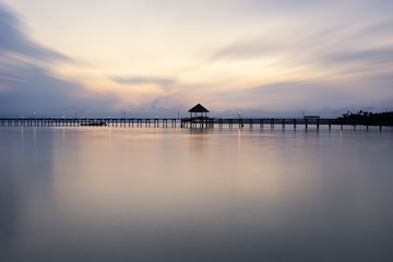 Fototapeta na wymiar A wooden bridge leading to the sea on a beautiful sunset light.