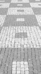 black and white photo of pavement with pattern of darker and lighter squares