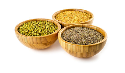 Whole seeds of cumin, coriander, mustard in rustic bowls on whit