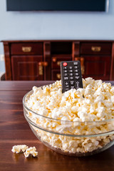 Popcorn in glass bowl and remote control