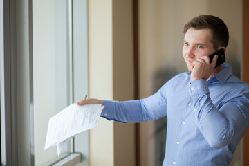 Happy businessman talking on the phone at office