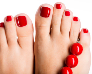 Closeup photo of a female feet with beautiful red pedicure