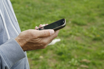 Man holding a mobile phone in her hand outdoors