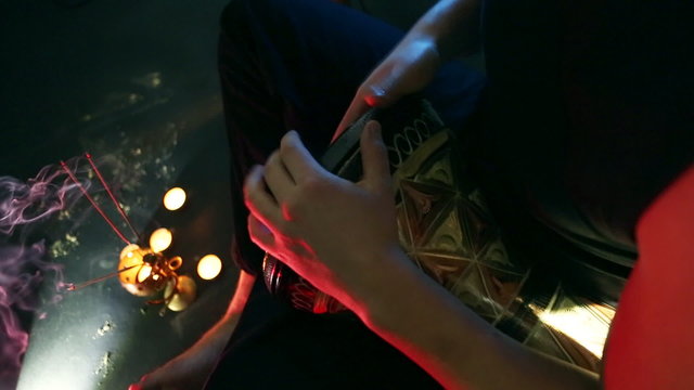 Male hands playing on darbuka, slow rhythm, incense and candles in the background.