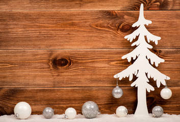 Decorative white christmas tree with silver and white balls on the wooden background.