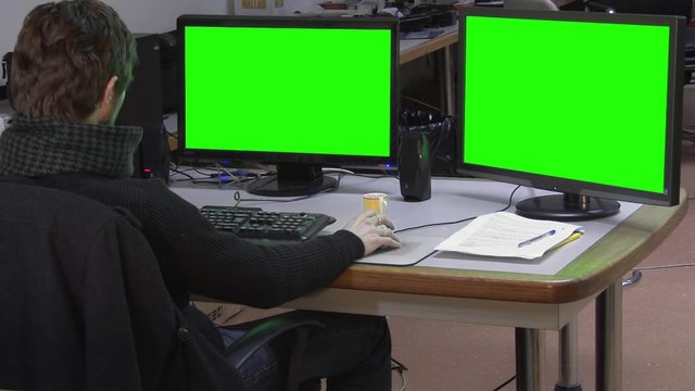 Worker in office with green screen monitors - 1080p. A man working in his complete office set with dual green screen monitors - Full HD
