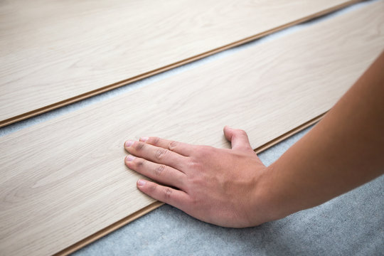 close up of hands installing new laminated wooden floor