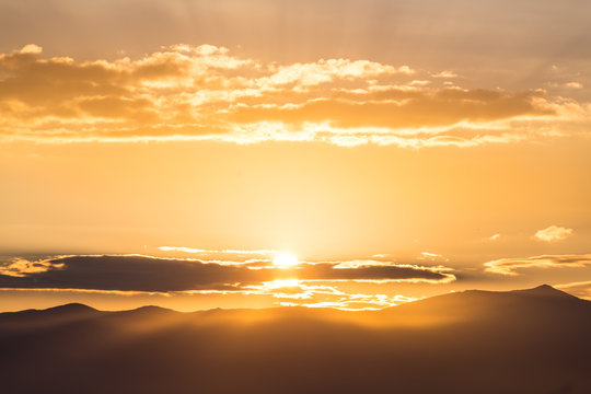 Scenic View Of A Beautiful Rich Orange Sunset Over The Mountains