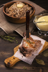 Stack of juicy pork chops, cream and corn sauce, boiled buckwheat on dark wooden table. Rustic style. Toned image. Selective focus