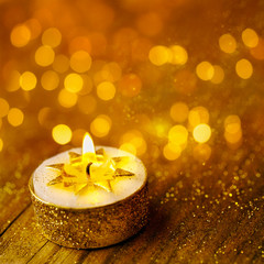 Burning candle on golden background