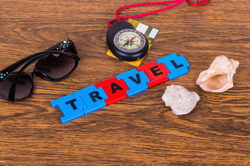 Надпись Travel, ракушки, очки и компас на деревянном фоне