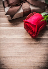 Boxed present expanded rosebud on wooden board holiday concept