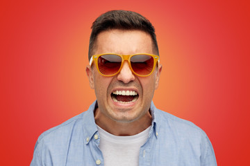 face of angry man in shirt and sunglasses over red