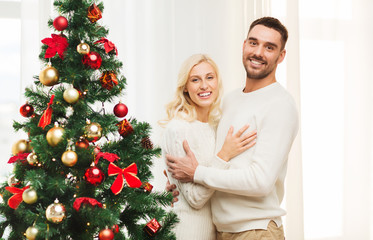 happy couple hugging near christmas tree at home