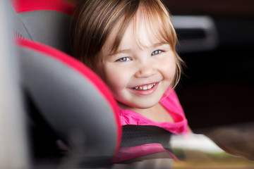 happy little girl sitting in baby car seat