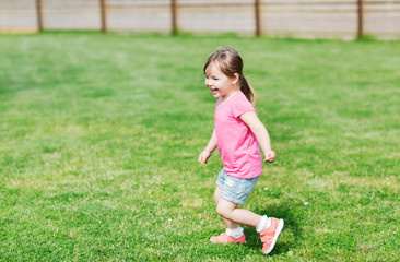 happy little girl running on green summer field