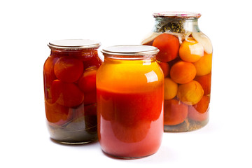 Glass jars of canned tomatoes and tomatoes juice on white backgr
