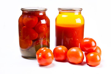 Glass jars of canned tomatoes and tomatoes juice on white backgr