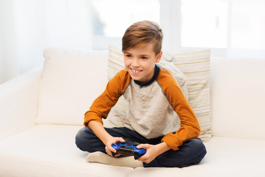 happy boy with joystick playing video game at home