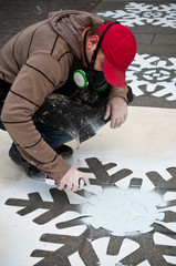 artiste peignant des flocons de neige sur le trotoir