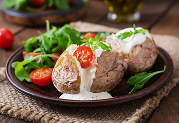 Baked potato filled with sour cream, arugula and tomatoes