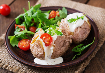 Baked potato filled with sour cream, arugula and tomatoes