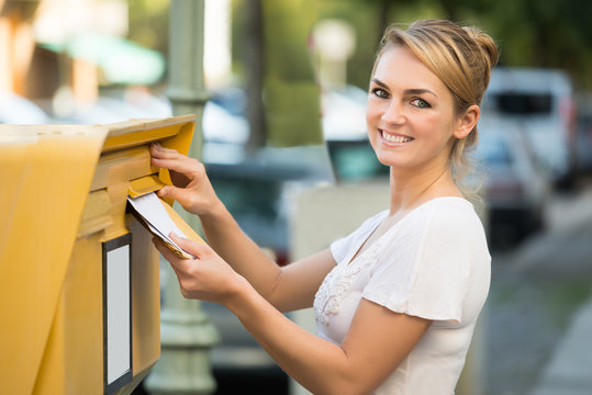 Woman Inserting Letter In Mailbox