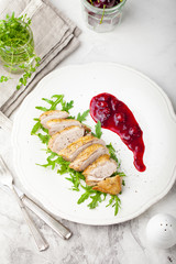 Duck breast meat with fresh salad, arugula and cherry sauce.