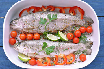 Two trouts in bowl with tomatoes, lime, pepper, parsley
