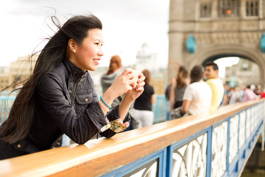 japanese woman taking a photo with her mobile phone from tower bridge