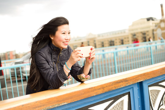 Japanese girl taking a photo from tower bridge