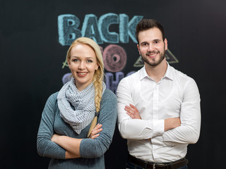Portrait of a smiling young man and woman in front of chalkboard
